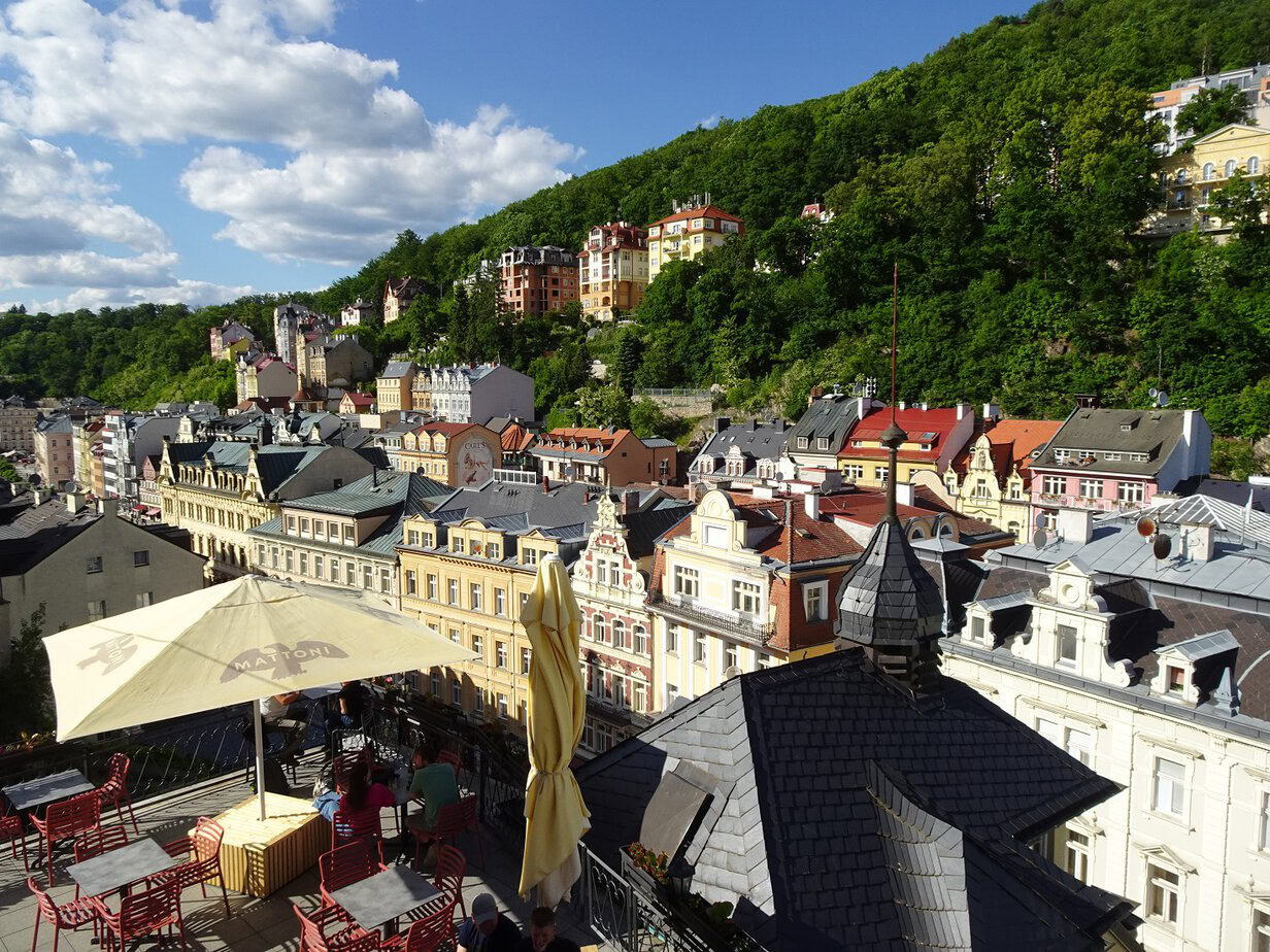 The view from the top of a building overlooking a town with a wooded hill nearby