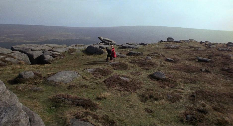 A man and woman running over a ridge strewn with erratic boulders