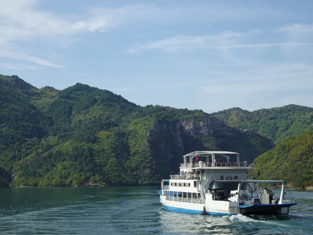 A ferry on a lake surrounded by wooded hills