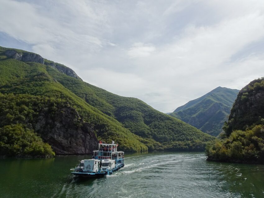 A ferry on a lake surrounded by wooded hills