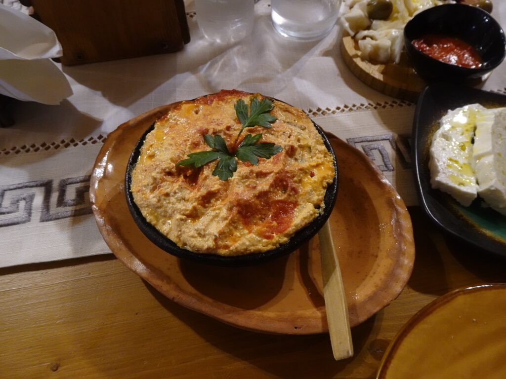 A plate containing a cheese-topped stew on a wooden table