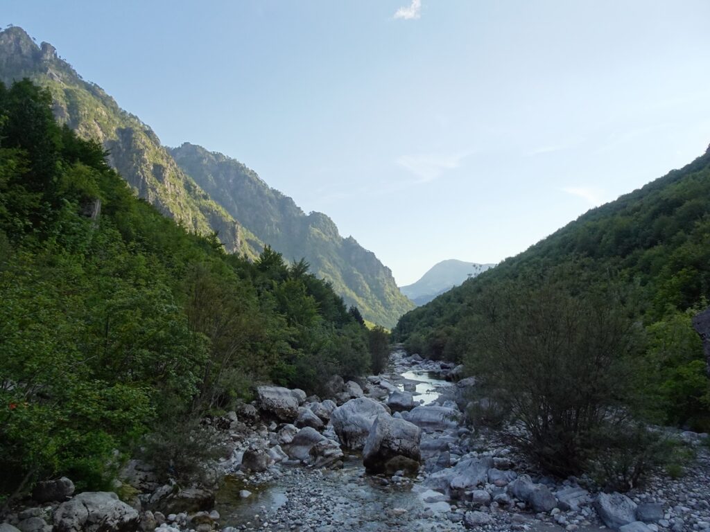 A wild river running through a canyon flanked by wooded slopes
