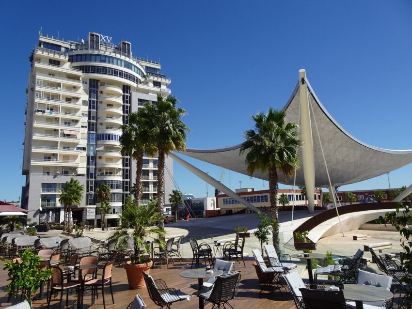 A large sail-like structure covering a bridge next to a tall apartment building