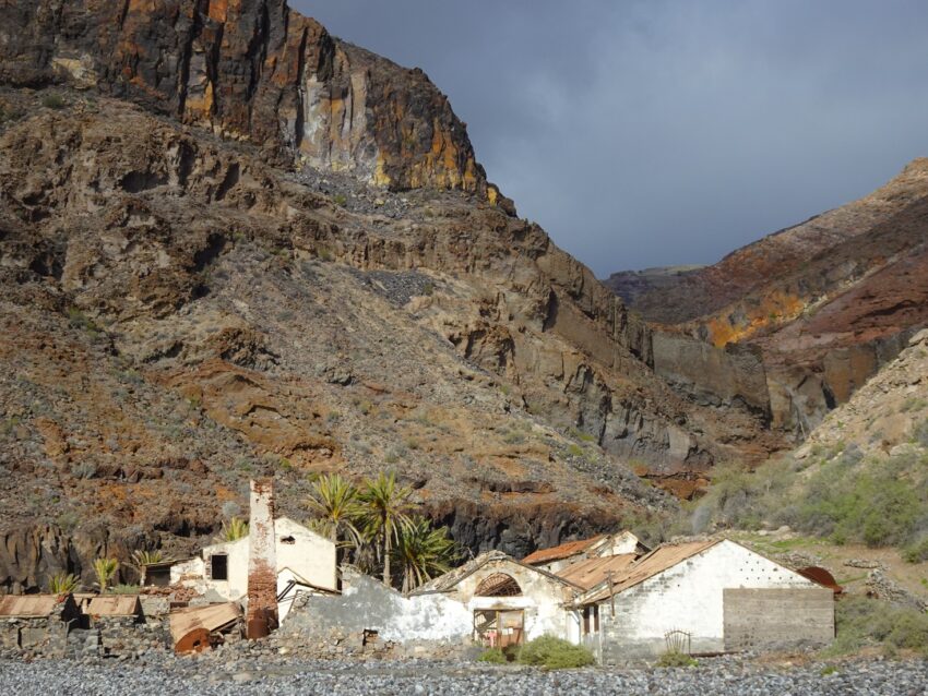 An abandoned factory with tall cliffs in the background