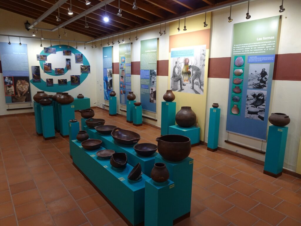 A museum display of pottery vessels with information boards in the background