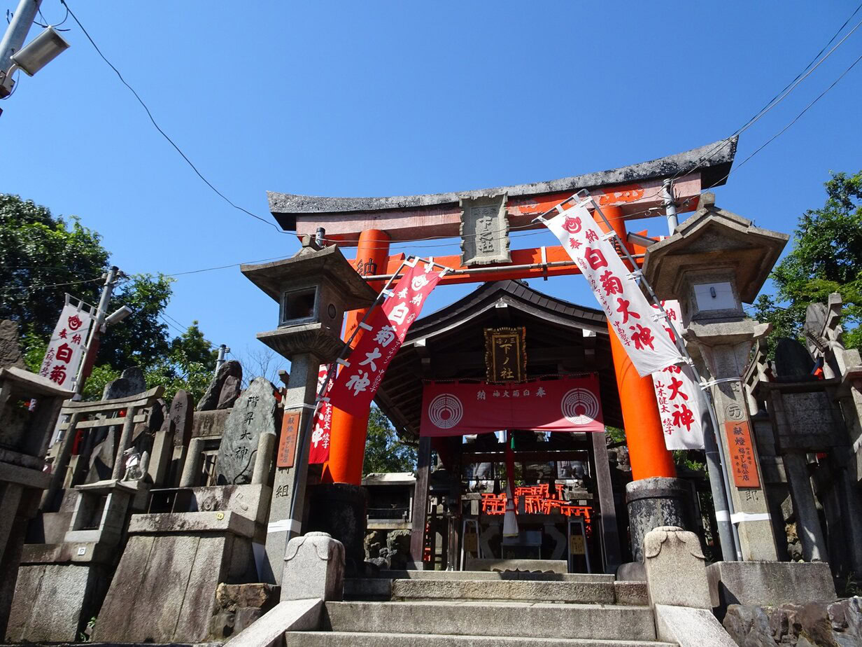 A wooden shrine building with a red gateway leading to it