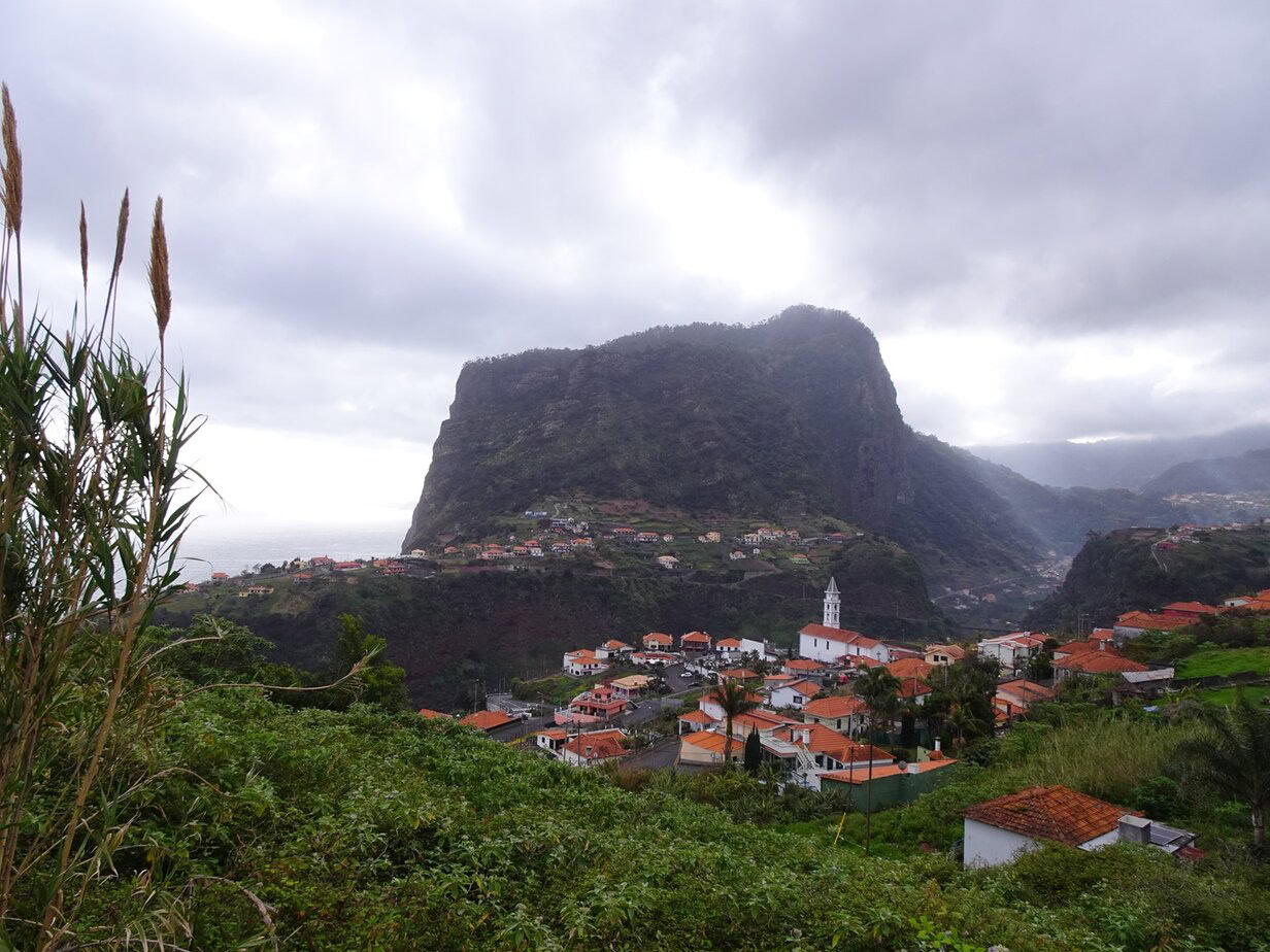 A tall table mountain towering over a tiny village of white houses