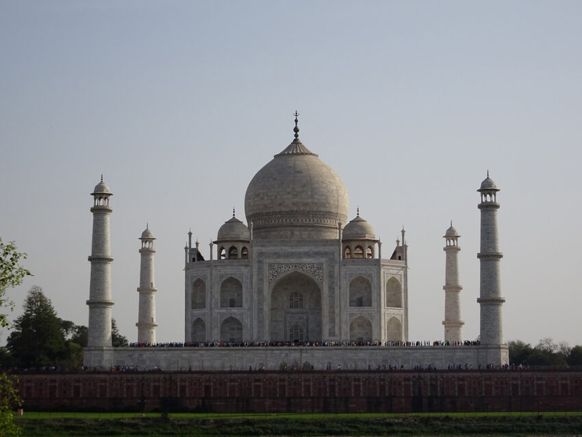 A view of Agra's Taj Mahal, a blindingly white mughal tomb with a large dome and slender towers surrounding it