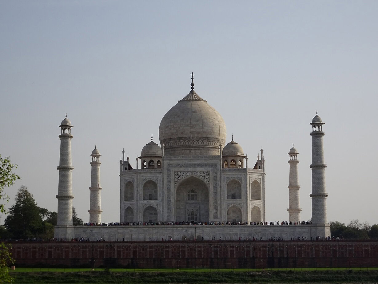 A view of Agra's Taj Mahal, a blindingly white mughal tomb with a large dome and slender towers surrounding it