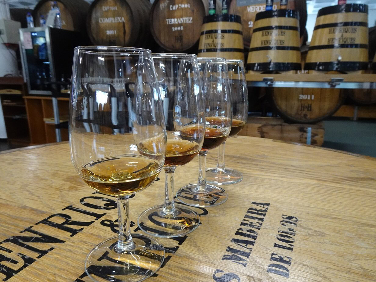 A row of four glasses containing dessert wine